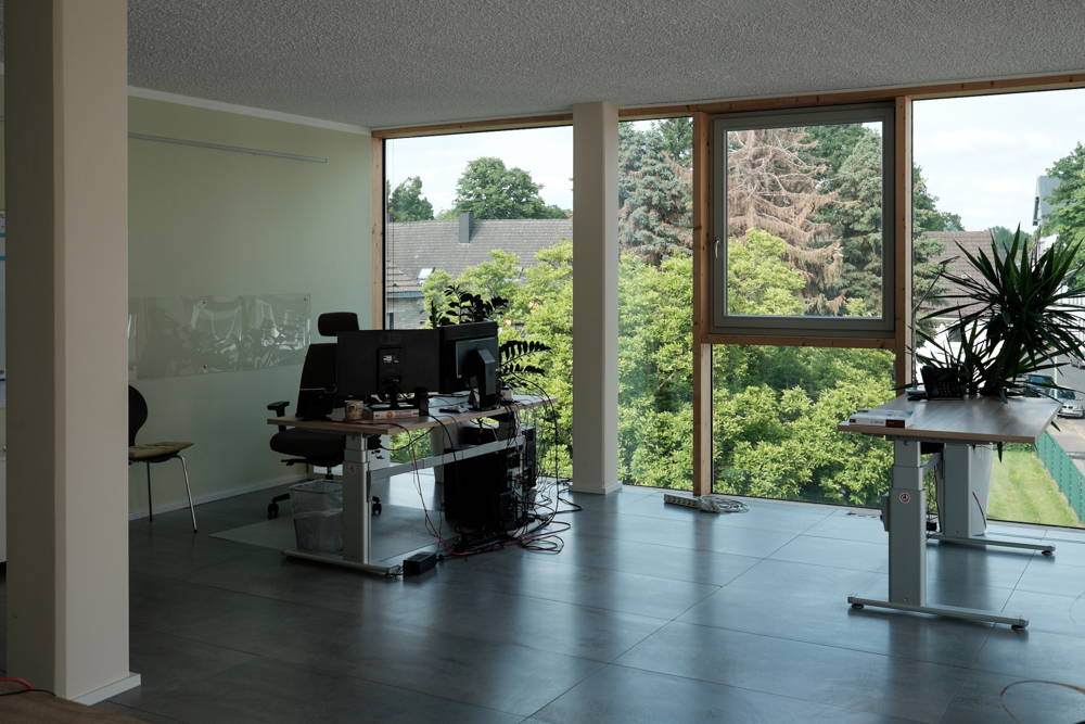 medienpark Büro mit zwei höhenverstellbaren Schreibtischen, Gartenblick und moderner Einrichtung.