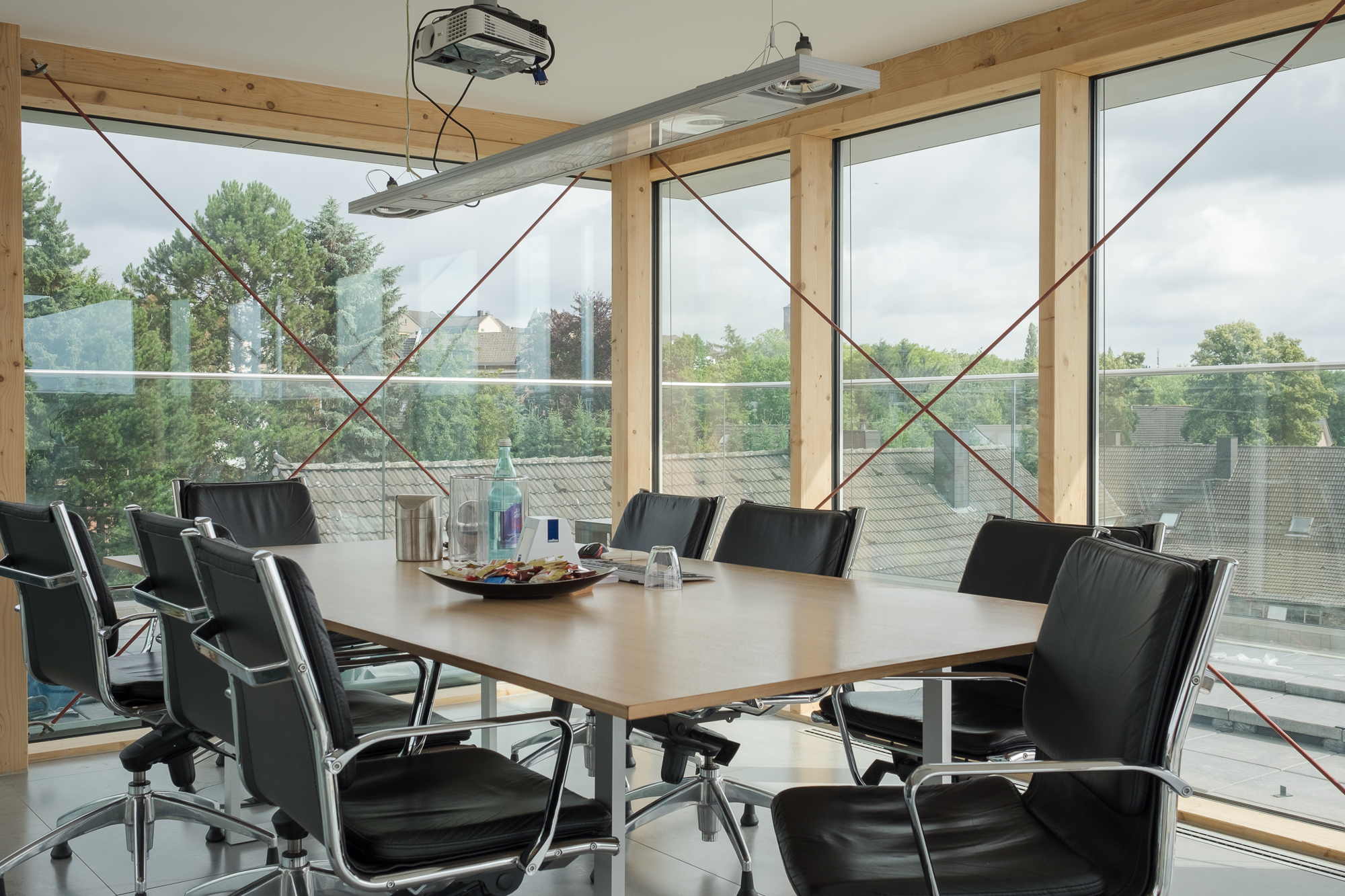Heller medienpark Konferenzraum mit Holzbalken, großem Tisch und Blick auf Bäume und Gebäude.