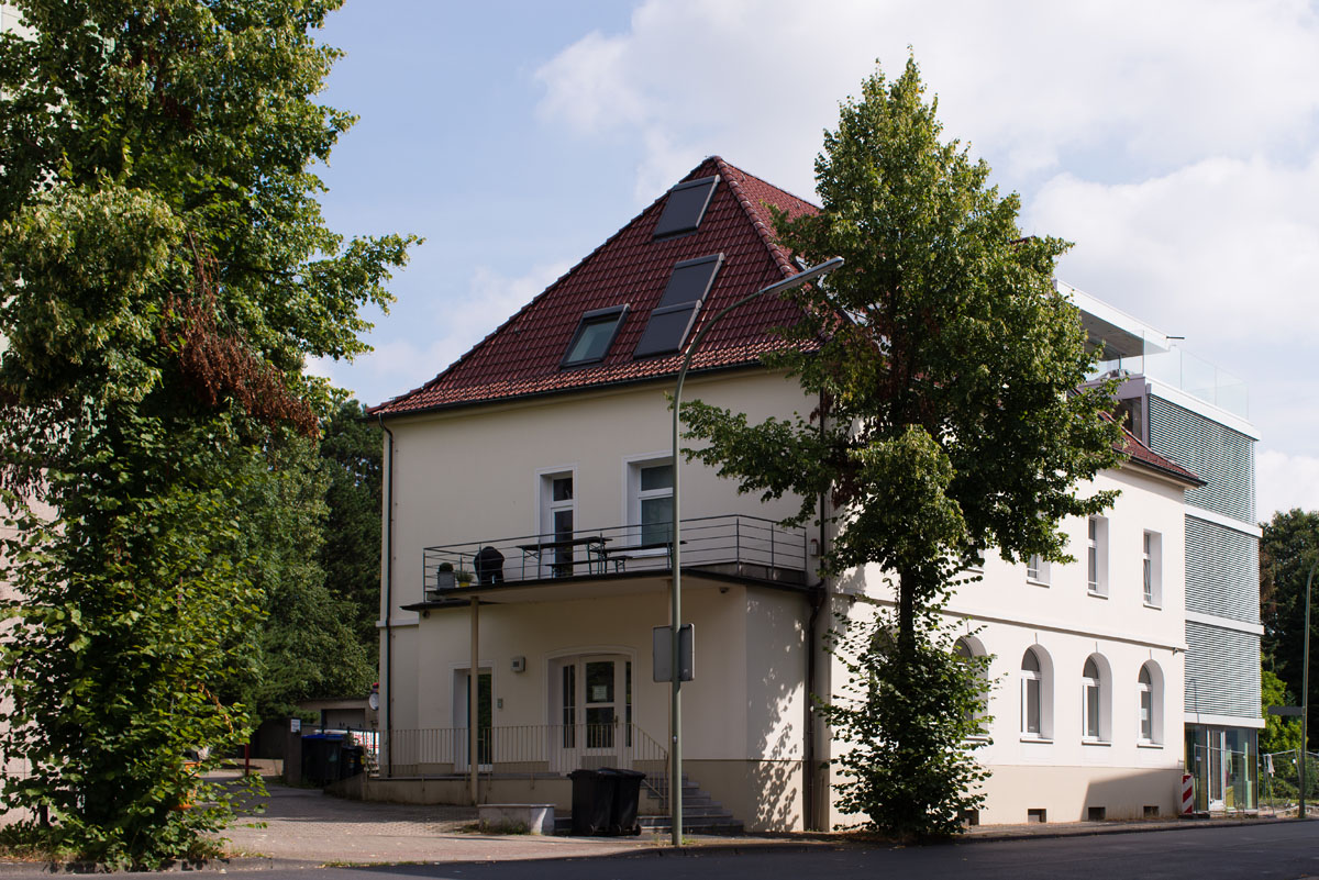 Mehrgeschossiges medienpark Gebäude mit rotem Satteldach, Solarpaneelen und einer kleinen Terrasse.